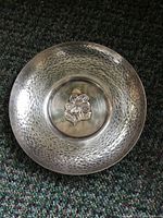 Top view showing hammered texture and central floral motif on silver dish.