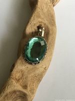 Close-up photo of the sterling silver pendant with faceted blue crystal stone resting on a piece of wood.