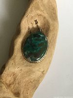 Front view of vintage sterling silver pendant with large oval mottled green and black boulder stone.