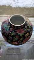 Top and side view of antique Chinese vase showing glossy black glaze and detailed multi-colored enameled floral decorations.