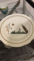 Photo showing top side of vintage Asian art porcelain plate with detailed illustration and Asian calligraphy.