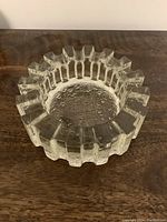Crystal glass dish placed on wooden surface showing its rough textured base and sculptural, angular rim.