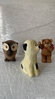 Front view of three vintage ceramic piggy banks: owl, dog, and bear