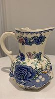 Side view of ceramic pitcher showing floral decorations and handle