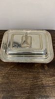 Covered silver plated rectangular dish with embossed trim and central handle for lifting lid.
