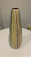 Front view of tall tapered pottery vase showing multicolor vertical striped pattern in beige, green, cream, and brown hues with glossy finish.
