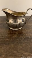Side profile of silverplated gravy boat showing ribbed pattern and curved handle.