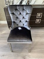 Front view of the dark grey velvet dining/accent chair showing button-tufted backrest and silver nailhead trim.