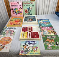 Overall display of the book collection showing various Walt Disney children's books and three audio cassette tapes in plastic trays.
