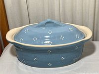 Full view of the light blue French tureen with lid on a white surface with curtains in the background.