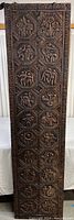 Full view of tall narrow wood panel showing all carved octagonal relief scenes and decorative border