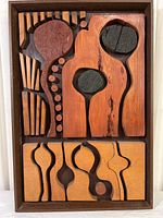 Full view of framed wooden mosaic artwork depicting abstract wildflowers with various wood tones and shapes.