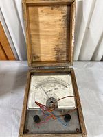 Open wooden box housing vintage Sim-ply-trol pyrometer with visible dial and connected wires.