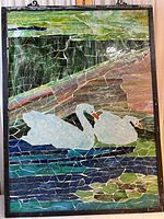Full view of the stained glass panel showing two white swans on water surrounded by foliage in various colors.