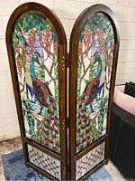 Two wooden-framed arched stained glass panels side by side