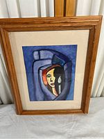 Full view of the framed abstract artwork of a woman in color, showing the wooden frame and glass.