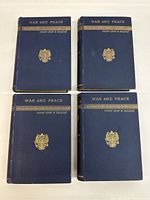 Front covers of the four volumes showing navy cloth bindings with gilt titles 'War and Peace' and Russian imperial crest
