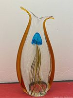 Front view of clear vase-shaped sculpture with amber side panels and internal blue jellyfish