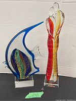 Both sculptures shown side by side on black surface with white background