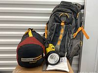 Photo of Eddie Bauer backpack alongside Eureka Whiskey Jack 200 sleeping bag in compression sack and flashlight.