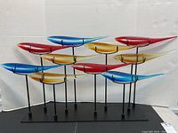 Full frontal view of the entire glass fish sculpture on stand showing arrangement of twelve fish and base.