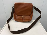 Front view of Fossil brown leather shoulder bag showing the flap with buckle closure and fabric strap.