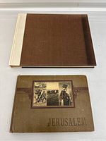 Two books, one large brown and beige hardcover and one smaller brown antique book titled 'Jerusalem'