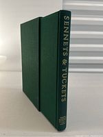 Book spine and slipcase standing upright, showing gilt title and cloth binding