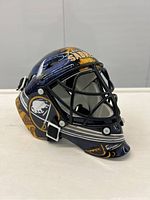Left side view of mini Buffalo Sabres goalie helmet showing team logo and autograph on top.