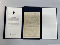 Open triptych box containing reproduction manuscript pages and introductory documentation sheet.