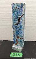 Front view of entire sculpture showing clear glass side and textured blue face