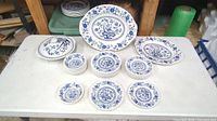 All 28 pieces of Wedgwood Blue Heritage dinnerware arranged on table showing various plates and bowls in set.