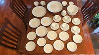 Photo showing full dinnerware set on table with plates, bowls, cups, saucers, and serving pieces spread out.