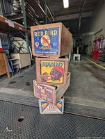Stack of four wooden crates showing colorful advertising labels on the fronts.