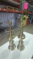 Pair of tall brass Stiffel lamps shown standing side by side on a flat surface, no shades, showing general shape and size