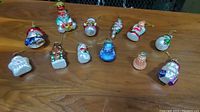 View of all twelve assorted Thomas Pacconi glass Christmas ornaments arranged on a wooden surface showing different styles and colors.