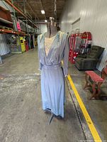 Full view of the adjustable ACME dress form wearing the blue silk Victorian dress and lace slip in a warehouse setting.