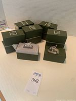 Six green Christofle boxes with two opened to display silverplate napkin rings topped with bird figurines