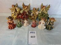 Front view of 7 wooden painted angel figurines, 3 children and 4 adults with gilt metal wings