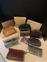 Full view of 12 clutch purses and 1 makeup bag of varied colors and materials placed on a white surface against black background.