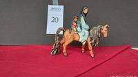 Front view of Goebel DeGrazia porcelain figure showing woman and child on horse with red cloth background.