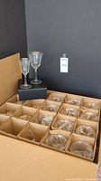 Overall view of multiple crystal goblets packaged in a box with compartments inside, with two goblets displayed on the box lid.