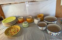 Wide view showing all dishes: yellow plates, yellow soup bowls, white dessert bowls, hand-painted serving bowls, cups with matching saucers, and pie dish.