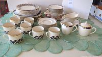 Full overview of dinner plates, salad plates, dessert plates, cups, saucers and serving pieces on table.