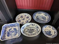Overview photo showing five blue and white china serving dishes with various patterns and shapes arranged on a dark surface.