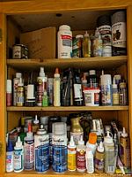 Shelf with various bottles, cans, and containers of glues, paints, and finishes