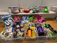 Wide view showing assortment of ribbons, curling ribbons, bows, and storage containers on a table and shelf.