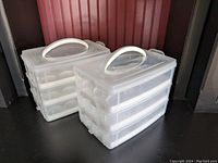 Two plastic clear plastic deviled egg carriers stacked with handles on top, each having three levels.