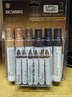 Front view of Ideaworks Furniture Repair Markers and filler crayons showing 6 markers and 6 crayons in different wood colors.