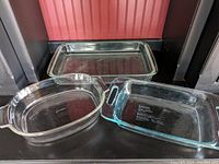 Three glass baking dishes arranged side by side: clear rectangular dish at back, two oval/rectangular dishes in front